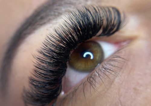 Detailed close-up of a woman's eye with styled eyelashes and groomed eyebrow.